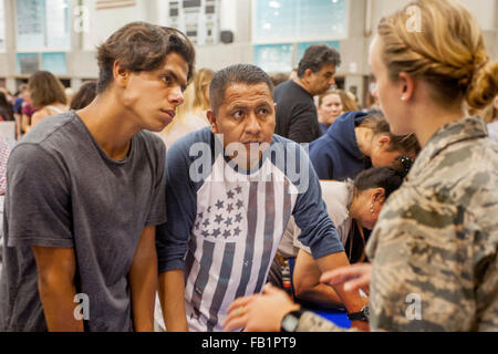 A concerned Hispanic father and son inquire about college Reserve Officer Training Corps (ROTC) opportunities from a US Air Force officer at a college fair in Aliso Viejo, CA. Stock Photo