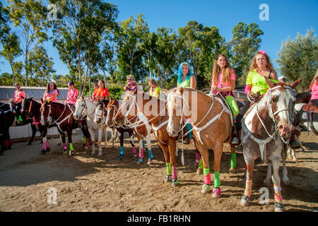 Multiracial adult women and teen girl equestrians group their horses after a riding meet in Laguna Woods, CA. Stock Photo