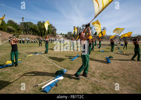 Multiracial high school marching band members practice waving banners before an area band competition in Mission Viejo, CA. Note prop rifle. Stock Photo