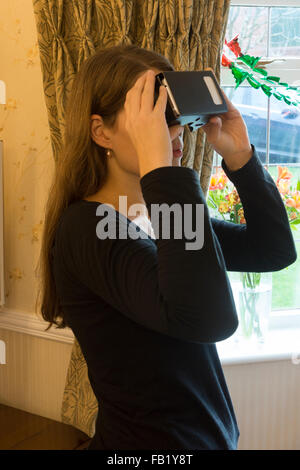 A woman using a Google Cardboard viewer received as a Christmas present Stock Photo