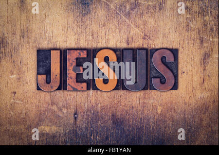 The word 'Jesus' written in dirty vintage letterpress type on a aged wooden background. Stock Photo