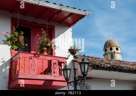 Red balcony and the tower of a church in background under blue sky Stock Photo