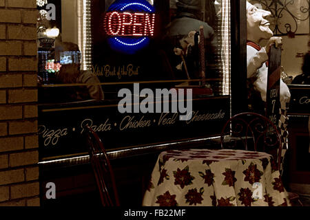 Storefront window of a restuarant with table and chairs outside and a statue of a baker Stock Photo
