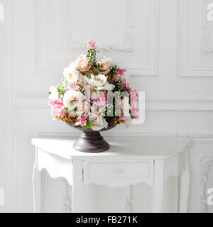 beautiful and delicate bouquet of buttercups and rose in a zinc vase on the table in white interiour Stock Photo