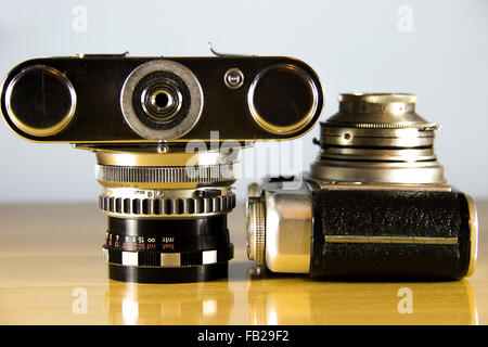 Two old analog 35mm cameras presented on a wooden table Stock Photo