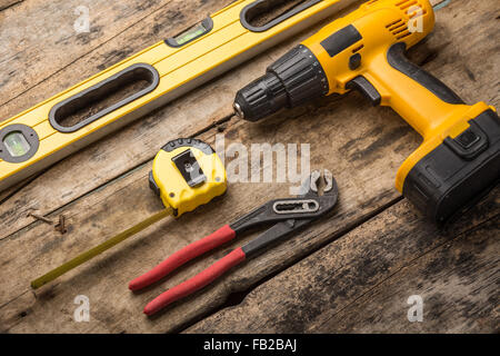 Construction tools on wooden background. Level, screwdriver or drill, tape and spanner top view image Stock Photo