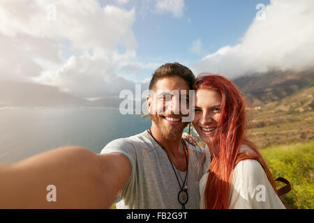 Cheerful young couple taking a selfie outdoors. POV shot man holding a camera taking a self portrait with his girlfriend. Stock Photo