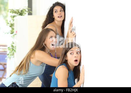 Three gossip girls listening through the neighbour wall at home Stock Photo