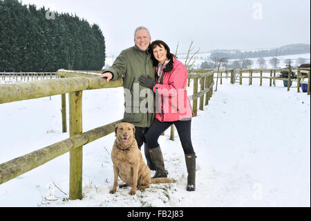 Middle aged couple walking their dog in a winter countryside Stock Photo