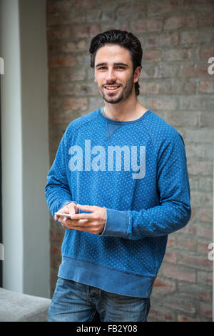 Handsome man using smartphone in living room Stock Photo