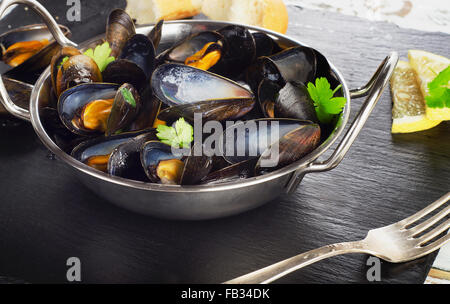 Boiled mussels in cooking dish on a dark background. Selective focus