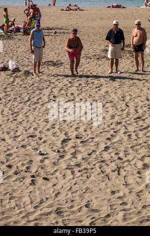 Groups of retirees playing petanque with steel bowls on the sandy beach of Las Vistas in Los Cristianos, Tenerife, Canary Island Stock Photo