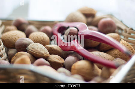 Assorted nuts in a star shaped basket with a red nutcracker on top. Stock Photo