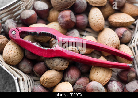 Assorted nuts in a star shaped basket with a red nutcracker on top. Stock Photo