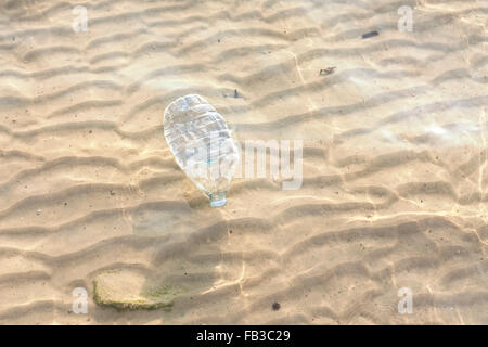 Plastic bottle in shallow sea water, environmental pollution concept. Stock Photo