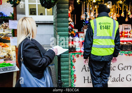 A journalist takes notes at a market, while looking at a security guard.  It comes after guards were accused of preventing photography and note-taking. Stock Photo