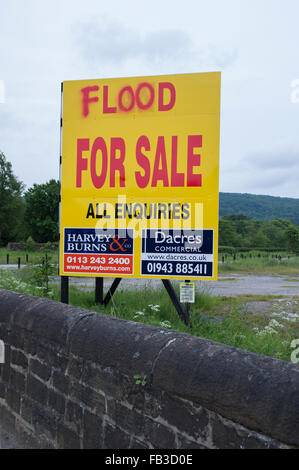 Irony, sarcasm, humour. Large sign advertising sale of land on floodplain - defaced and the word 'land' changed to 'flood.' Otley, England, GB, UK. Stock Photo