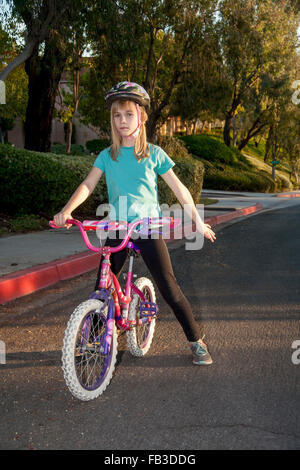 A tween girl bicyclist signals a right turn using her left arm on a