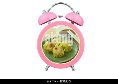 conceptual art : shu mai time : shu mai and sauce within pink alarm clock isolated on white background Stock Photo