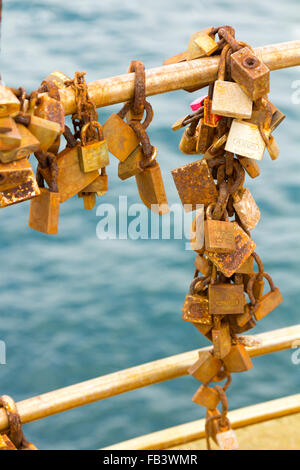 Rusty padlocks on a railing by the sea Stock Photo
