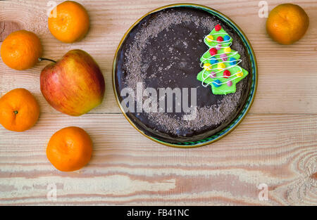 On the table is chocolate cake and fruit: apples and tangerines. The view from the top. Stock Photo