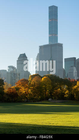 Autumn sunrise in Sheep Meadow Central Park with view on Midtown Manhattan skyscrapers, including 432 Park Avenue. New York City