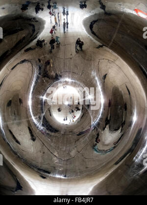 Distorted reflections are seen of sightseers looking underneath at 'The Bean,' the popular nickname for 'Cloud Gate,' a 110-ton elliptical sculpture in Millennium Park in Chicago, Illinois, USA. British artist Anish Kapoor created the shiny monument with pieces of stainless steel that were welded together and then highly polished to visually eliminate all the seams. The artwork took two years to complete and was unveiled in 2006. It has since become one of the major tourist attractions in the Windy City. Stock Photo