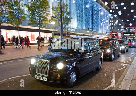 Christmas lights decorations London taxi cab driver waiting in traffic queue outside John Lewis Department Store building in Oxford Street West End UK Stock Photo