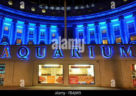 London Aquarium illuminated sign above café windows with floodlighting on the old County Hall building on the Thames embankment England UK Stock Photo