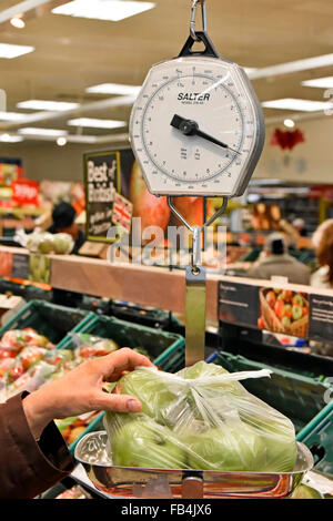 Salter weighing scales being used by a customer shopping in a  fruit and vegetable department of a Tesco supermarket to weigh apples London England UK Stock Photo
