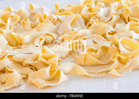Hand made italian pasta, called 'reginelle', on wooden board with flour. Stock Photo