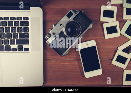 retro camera and some old photos on wooden table. Vintage look Stock Photo