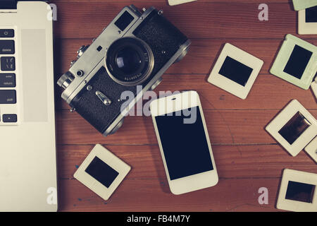 retro camera and some old photos on wooden table. Vintage look Stock Photo