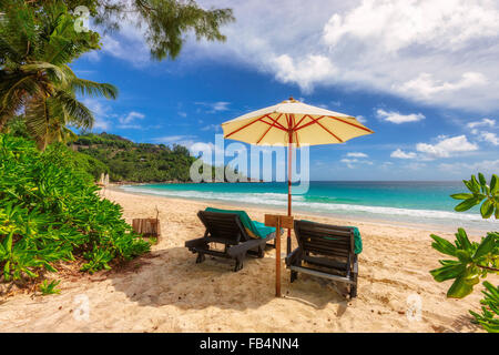 View of nice tropical empty sandy beach with umbrella and beach chair, Mahe Island, Seychelles Stock Photo