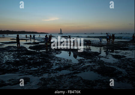 Silhouetted people by rock pools in the Pacific Ocean at Tamarindo, Costa Rica, at sunset. Stock Photo