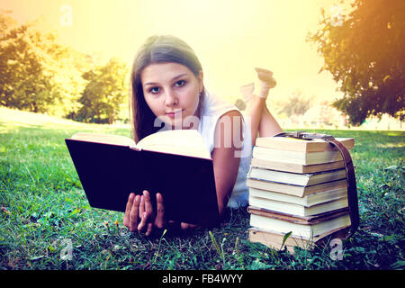 Student girl reading a book on campus grass. Education conceptual image. Instagram vintage picture. Stock Photo