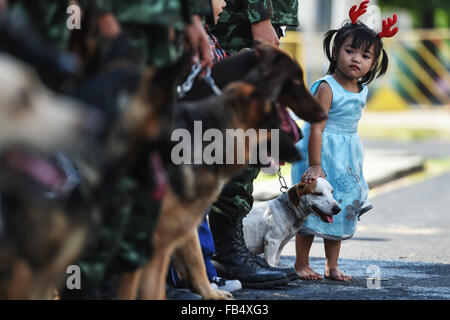 Beijing, Thailand. 9th Jan, 2016. A girl poses for photos with army dogs during a public opening event marking the Thai Children' s Day at the Royal Thai Army 2nd Cavalry Division based in the north of downtown Bangkok, Thailand, Jan. 9, 2016. Thailand opened a number of its military bases to the public while the Thai Children' s Day is observed on the second Saturday in January. © Li Mangmang/Xinhua/Alamy Live News Stock Photo