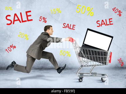 Businessman with laptop in shopping cart Stock Photo