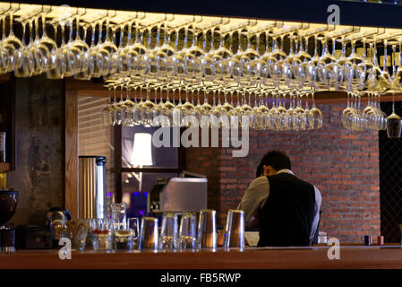 Group of empty wine glasses hanging from metal beams in a bar Stock Photo