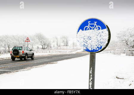 Vehicle driving on a country road in dangerous snowing conditions, with the cycle track covered in snow, Ayrshire, Scotland, UK Stock Photo