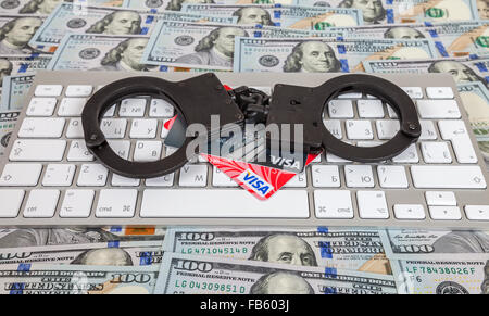 Steel handcuffs and credit cards lying on a computer keyboard on the background of dollars Stock Photo