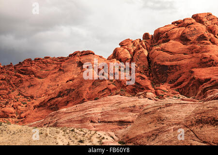 Climbers scramble up and down rocks as storm clouds close in on the Calico Hills of Red Rock Canyon National Conservation Area Stock Photo