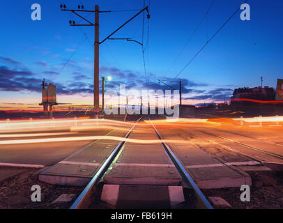 Railroad crossing with car lights in motion at night. Stock Photo