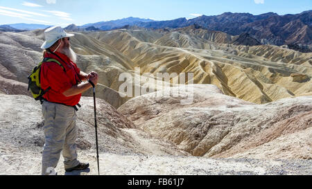 Man enjoys view from Death Valley's famous Zabriskie Point of surrounding desert hills. Stock Photo