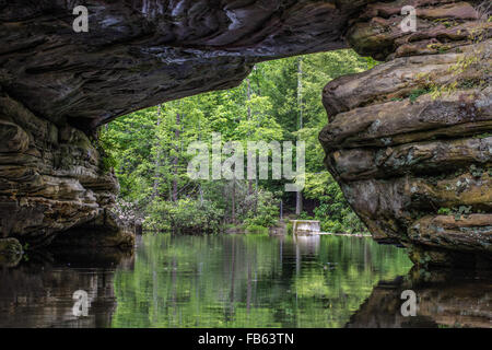 A sandstone arch over an inland lake in Pickett State Park in Tennessee. Visitors are able to rent kayaks and explore the arch. Stock Photo