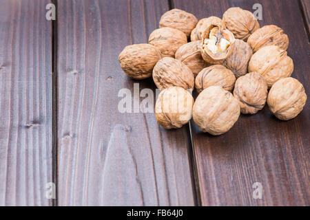 Walnut kernels and whole walnuts on rustic old wooden table Stock Photo