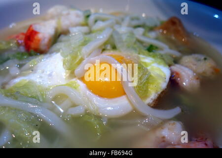 A bowl of Asian Udon noodle soup with seafood, egg and vegetables Stock Photo