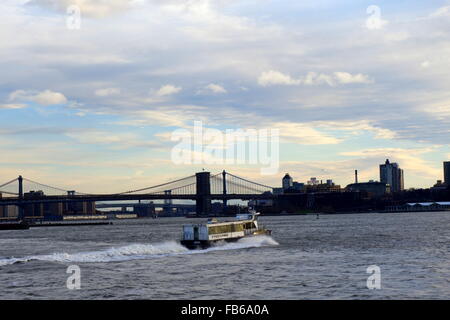 Moving NY Waterway ferry and early morning view of the Brooklyn Bridge on the East River, New York City, New York, USA Stock Photo