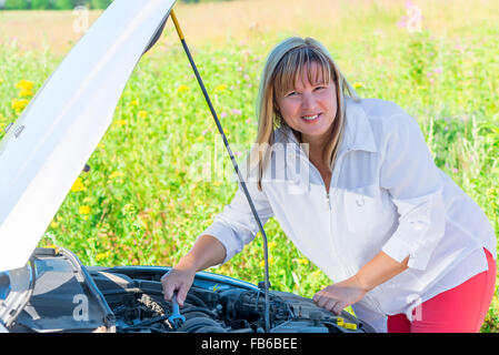 happy woman repairing the car on an empty road Stock Photo