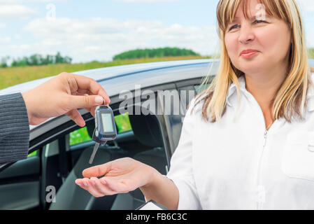the seller presents the woman key from the new car Stock Photo